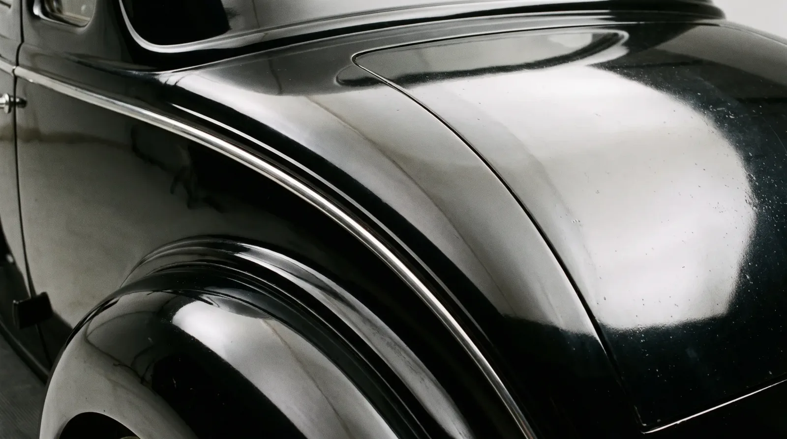 Stamped steel panel sweeping into a 1930s trunk lid seam