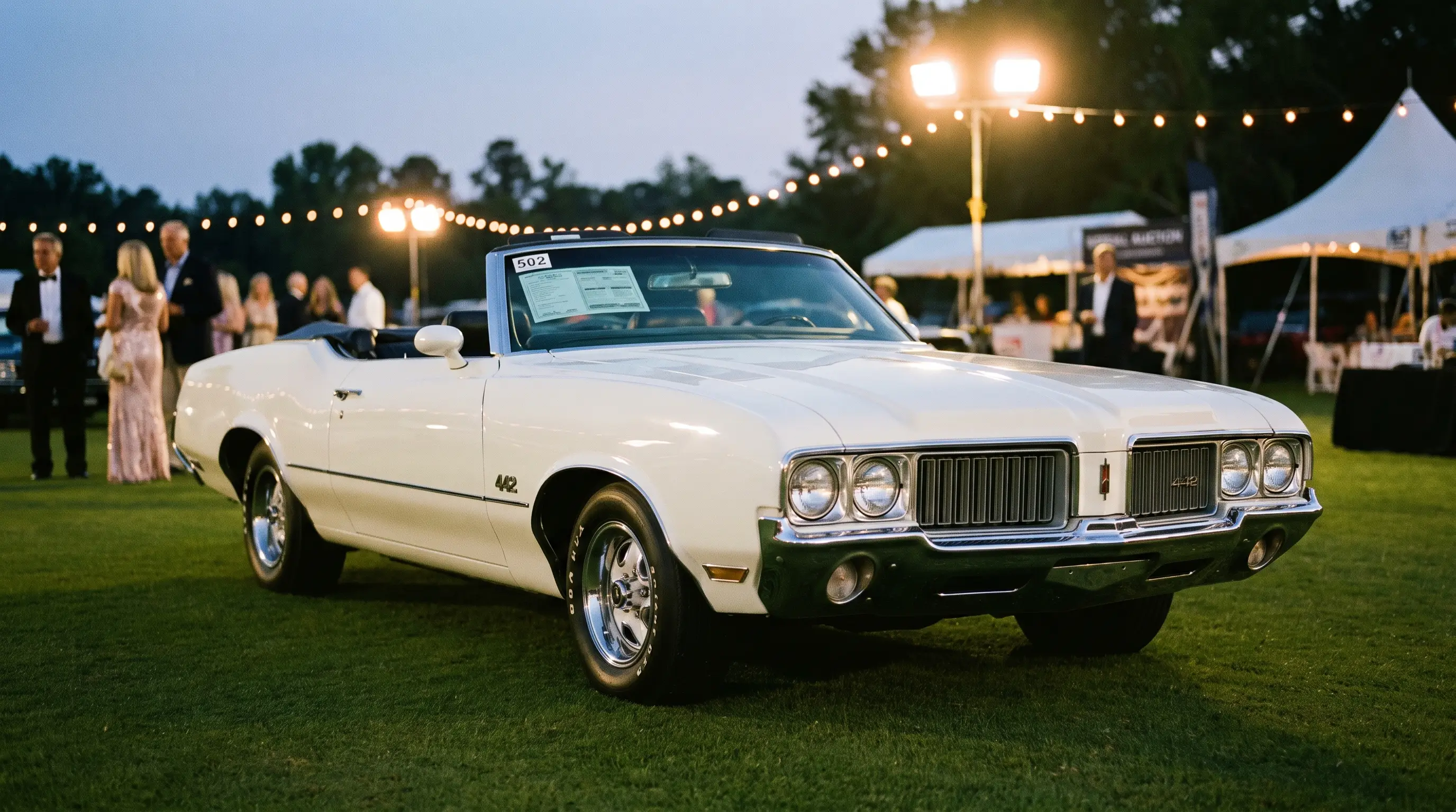 White classic Oldsmobile 442 displayed at an evening collector car auction