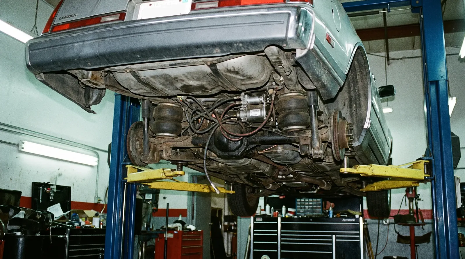 1980s Lincoln Continental Mark VII on a workshop lift showing air suspension underside