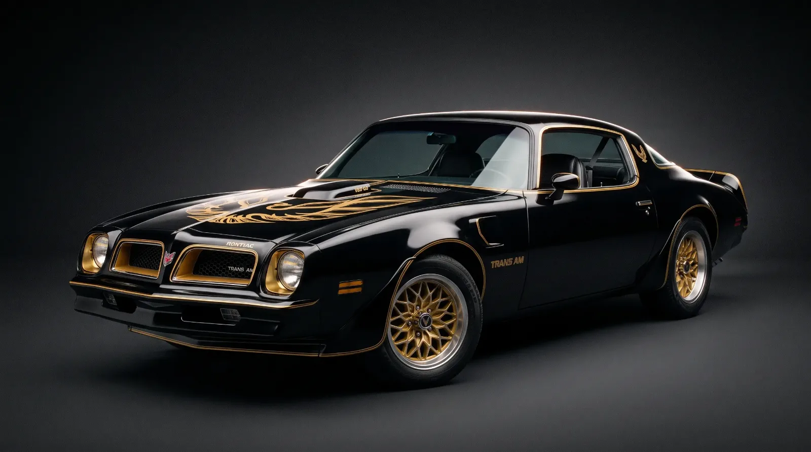 Studio close-up of a black and gold 1976 Pontiac Trans Am Special Edition showing the gold screaming chicken hood decal and gold wheels
