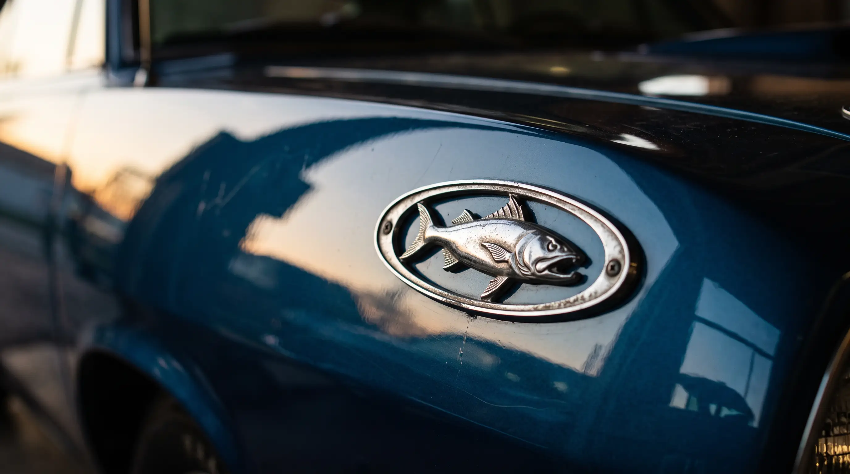 Close up of a classic Plymouth Barracuda fish emblem badge with dramatic light reflections