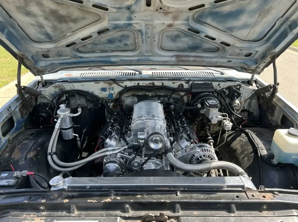 C10 engine bay -- modern V8 swap under a weathered original hood