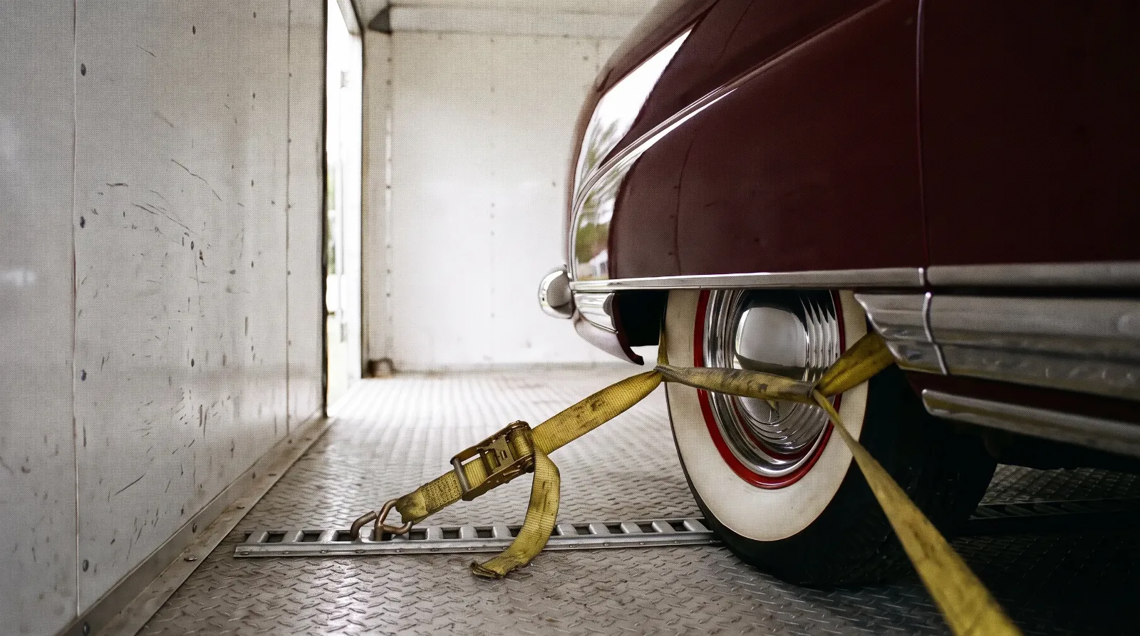 A wheel strap inside an enclosed trailer with a 1949 Hudson Commodore
