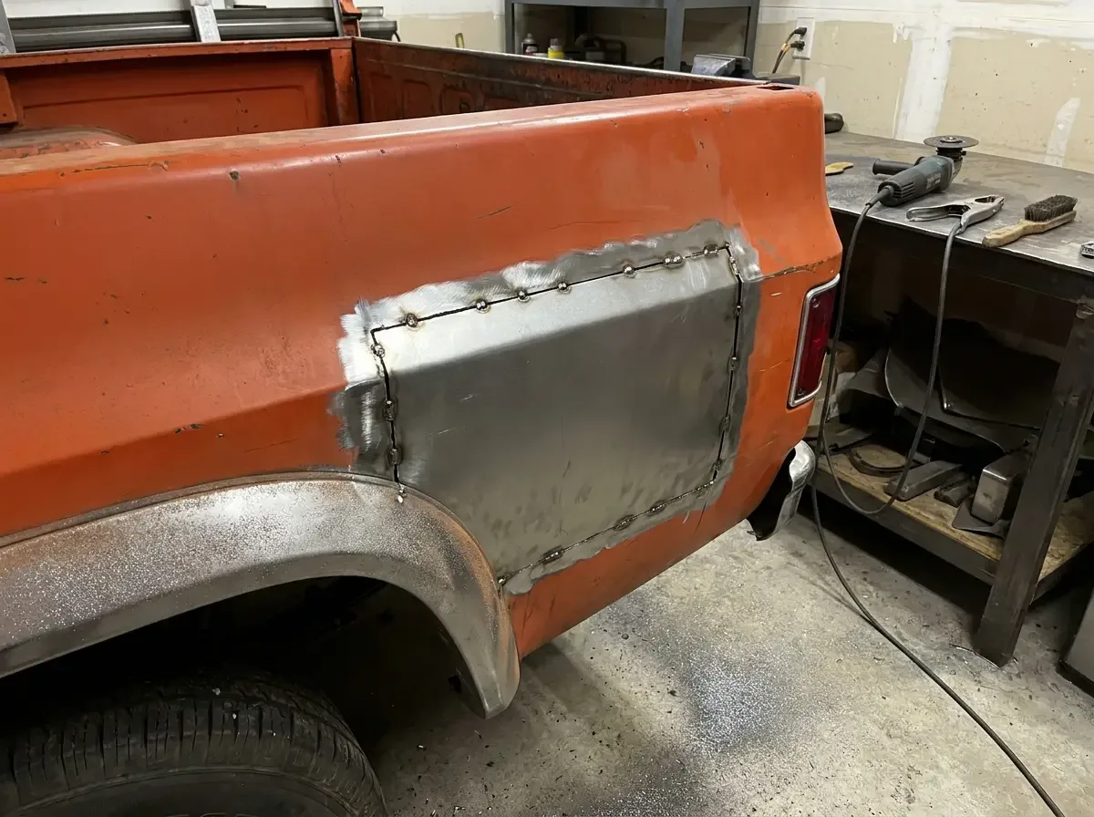 1970s Chevrolet C10 quarter panel -- fresh patch panel tack-welded in