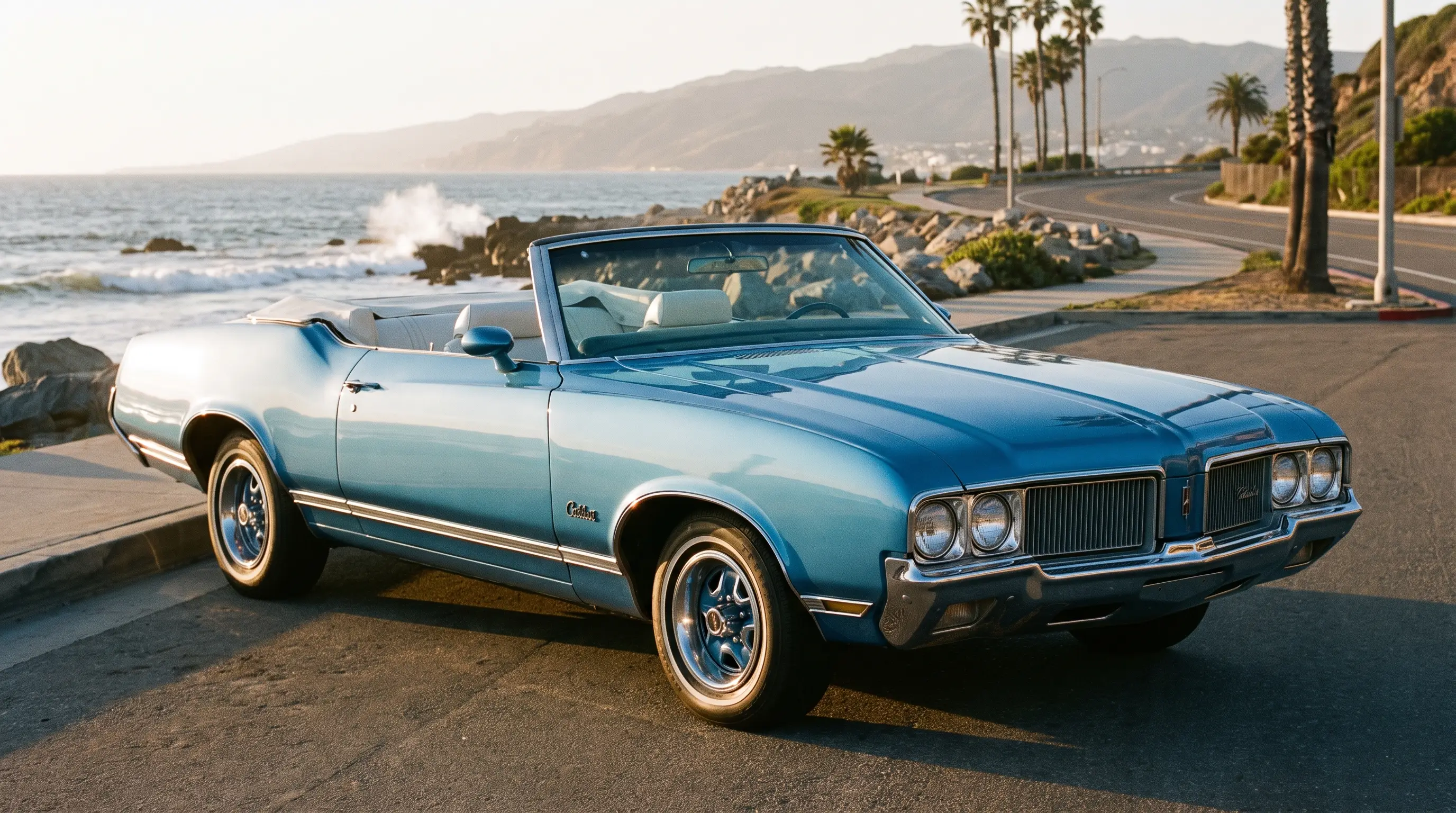 Sky blue Oldsmobile Cutlass convertible with top down along a coastal boulevard at golden hour