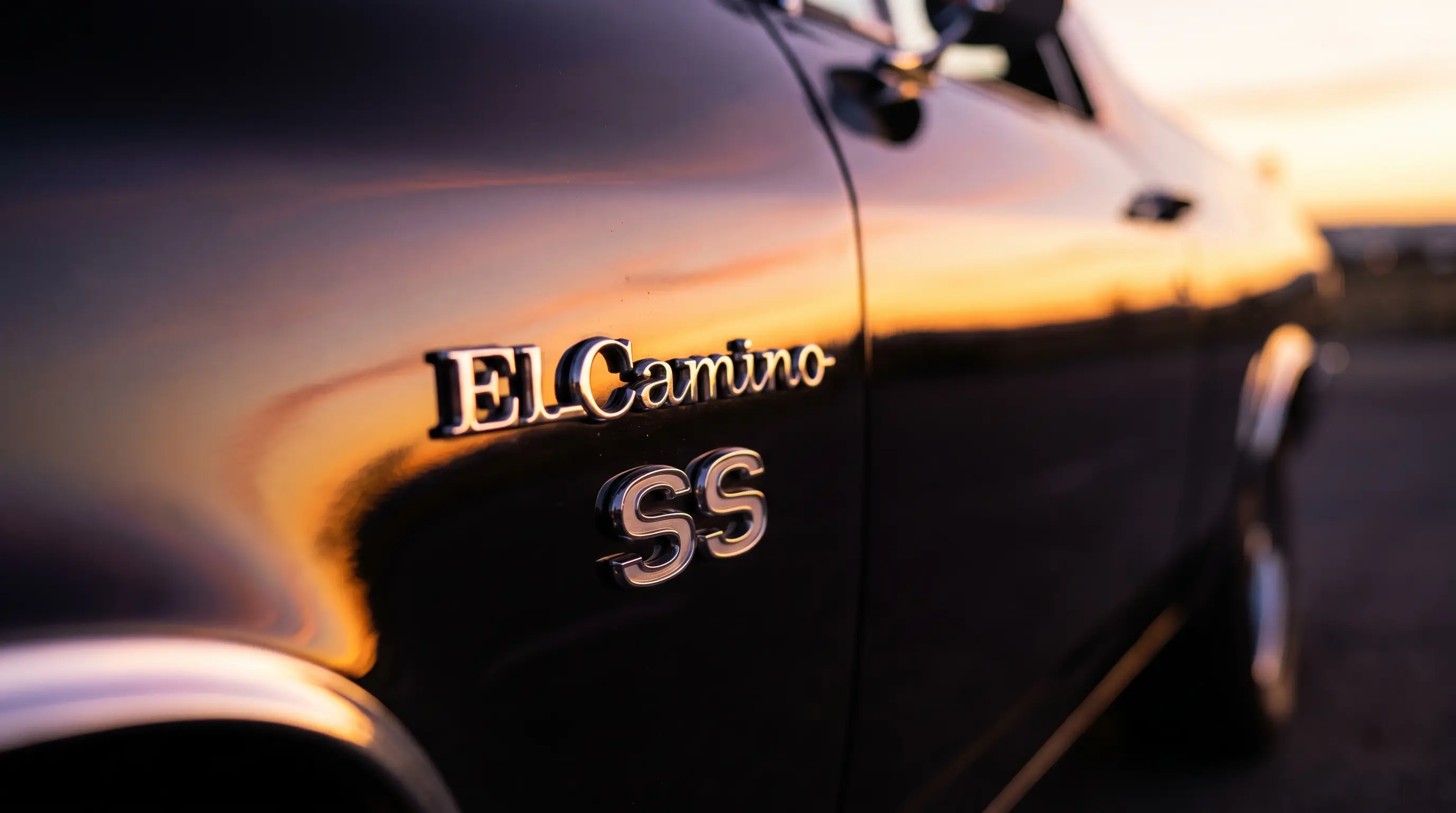 Close up of a chrome El Camino SS badge on black fender under warm sunset light