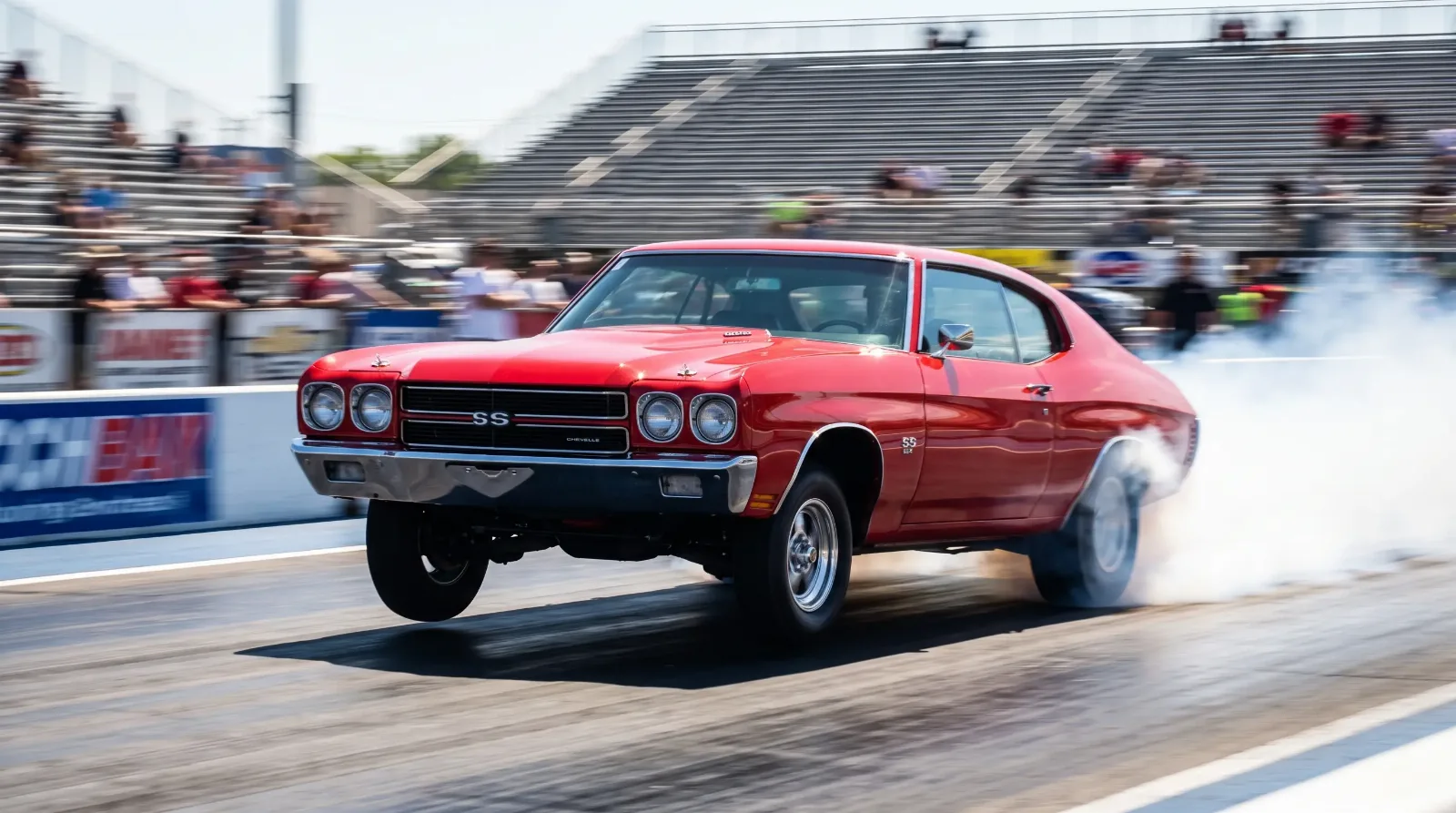 Red 1970 Chevrolet Chevelle SS 454 launching hard down a drag strip with tire smoke
