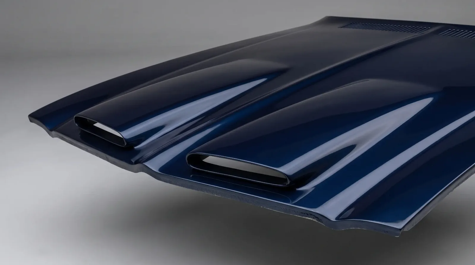 Studio detail shot of a Pontiac Firebird Formula twin-scoop fiberglass hood on a dark blue second-generation car