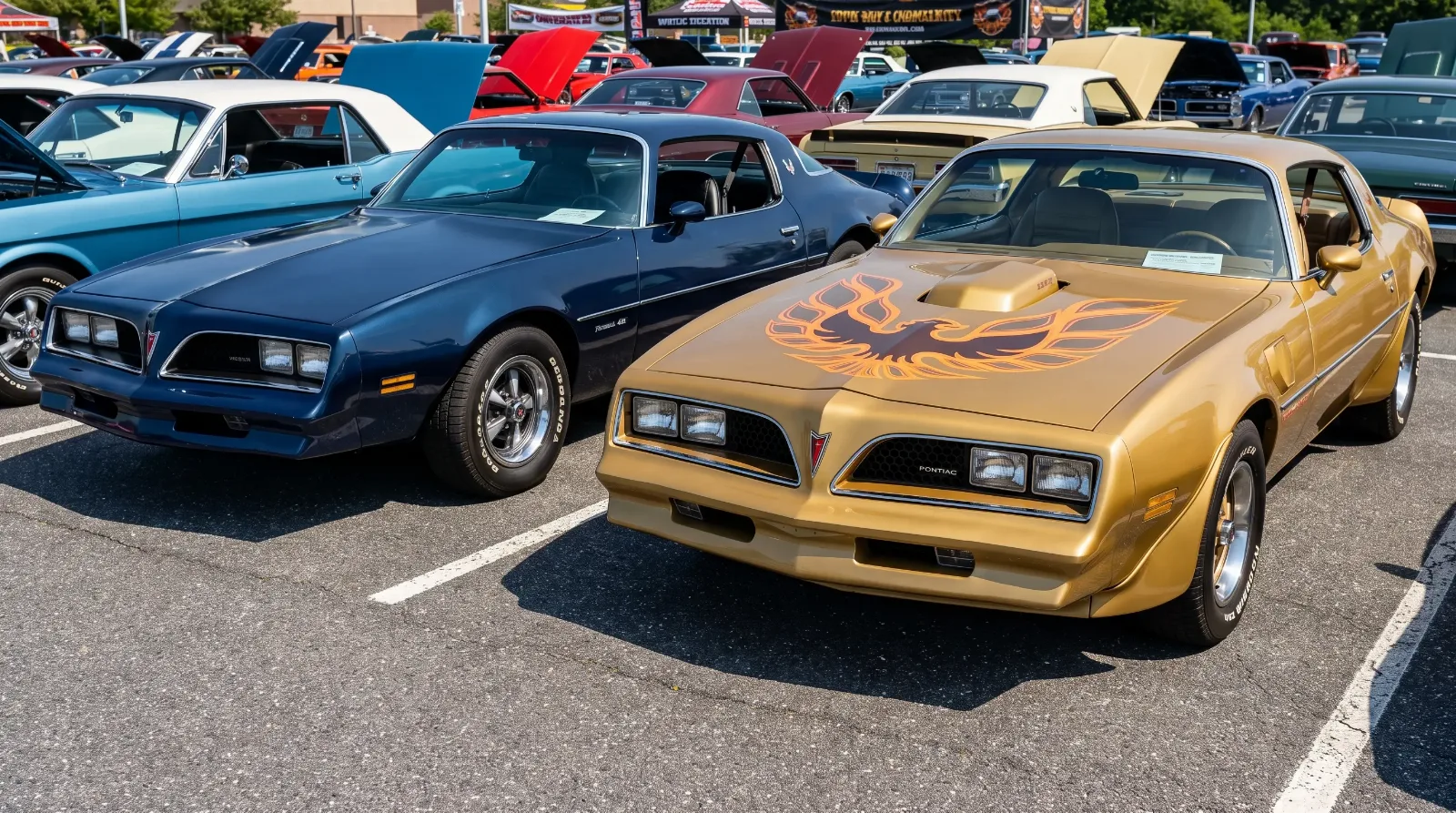 Dark blue 1978 Pontiac Firebird Formula 400 parked beside a gold 1978 Trans Am with shaker hood scoop at a car show