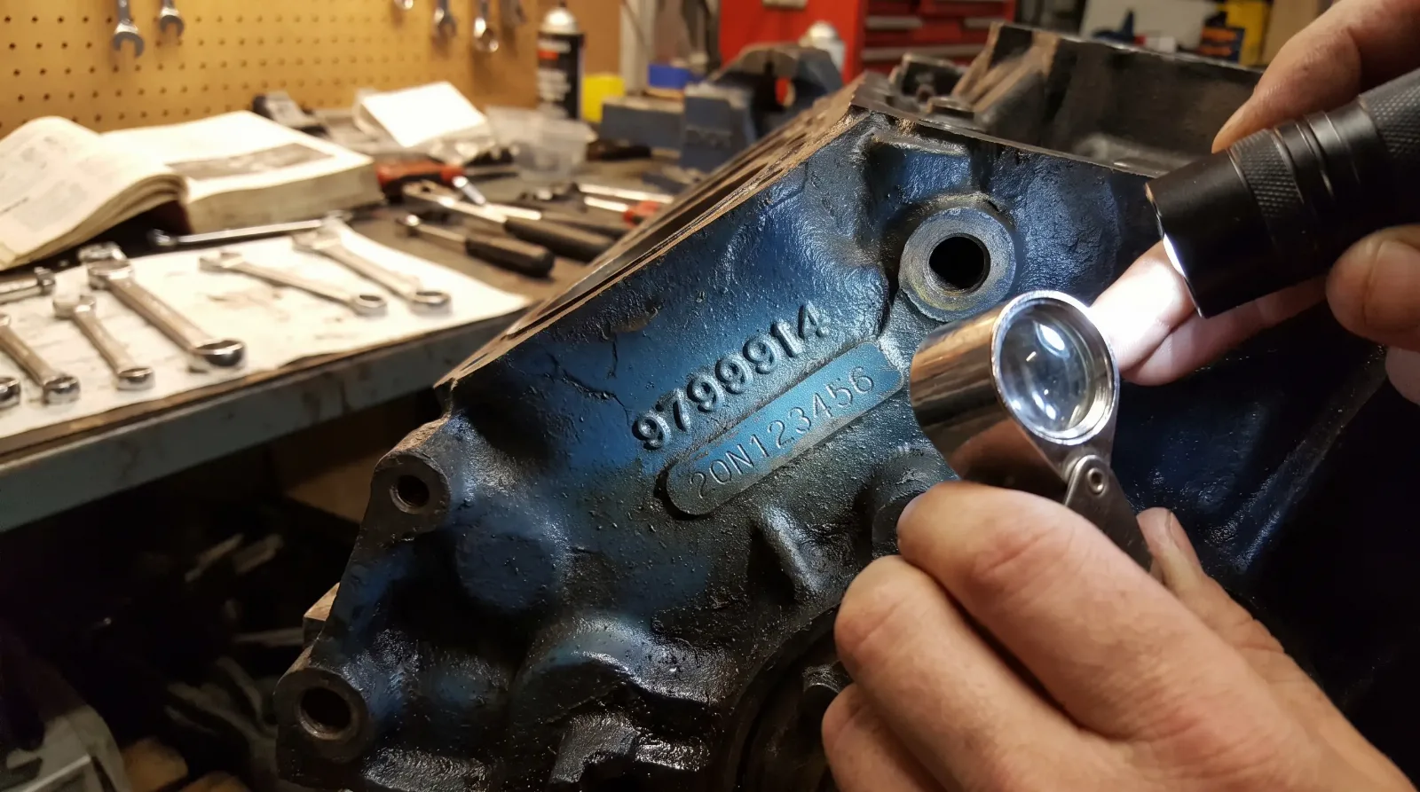 Close-up of a Pontiac 400 engine block casting number and stamp pad inspected with a loupe and angled work light