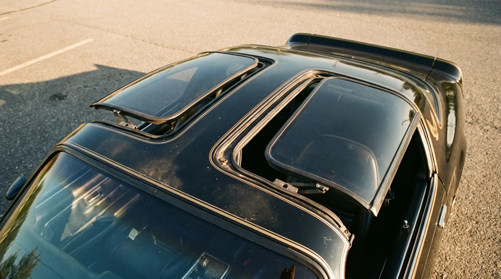 Open T-top roof panels on a late-1970s Pontiac Firebird Trans Am showing the removable glass panels and center bar