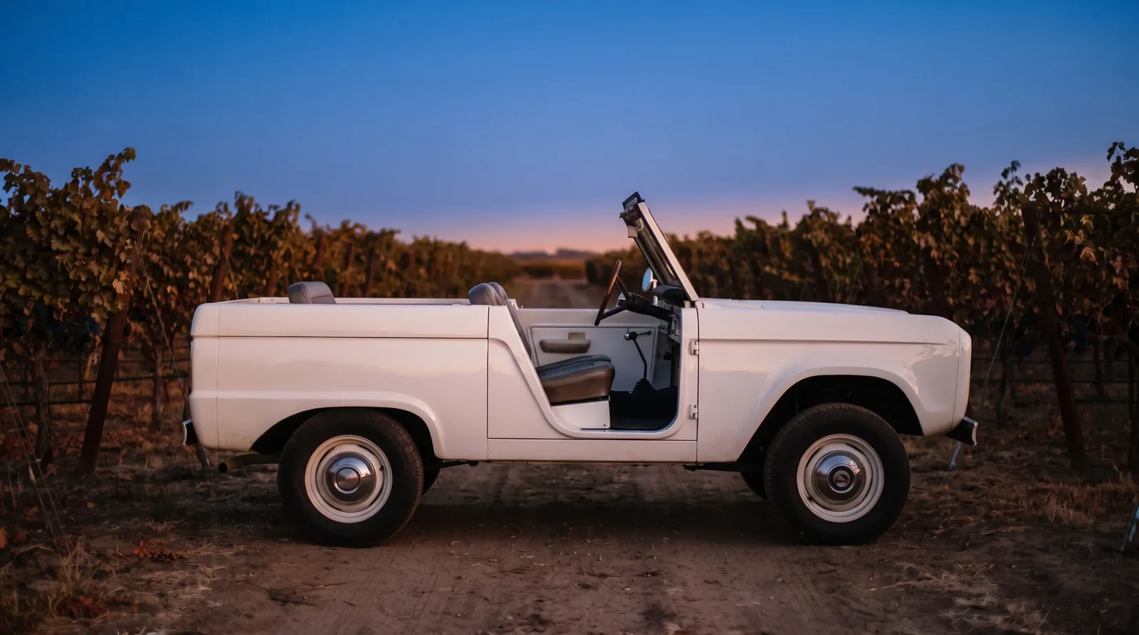 1966 Ford Bronco roadster, doorless in a vineyard at dusk