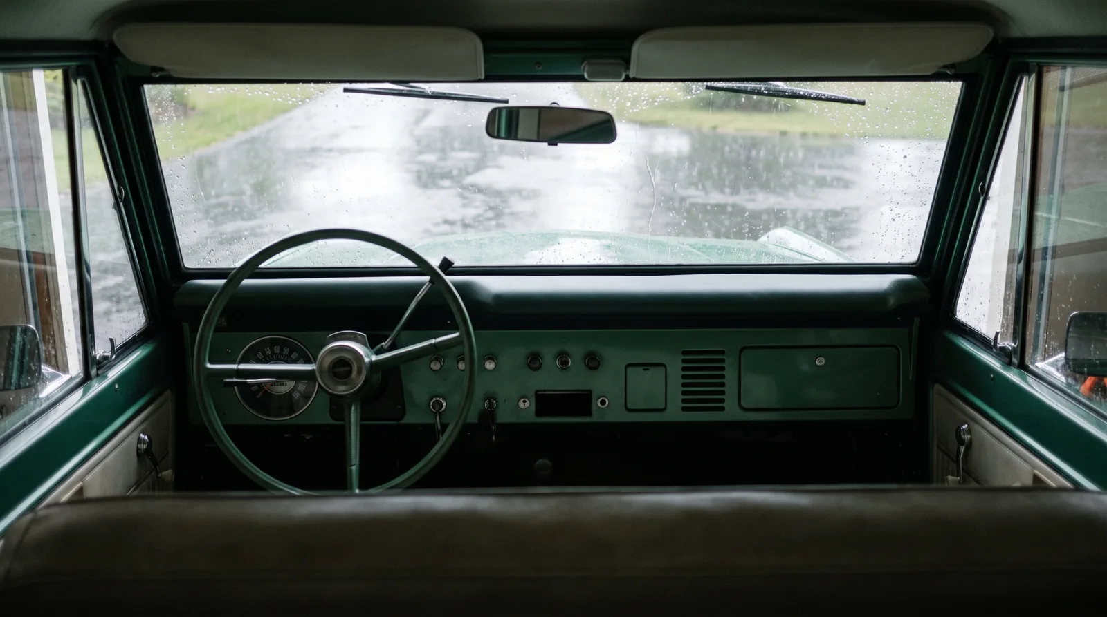 1966 Ford Bronco wagon, rain seen through the windshield from inside