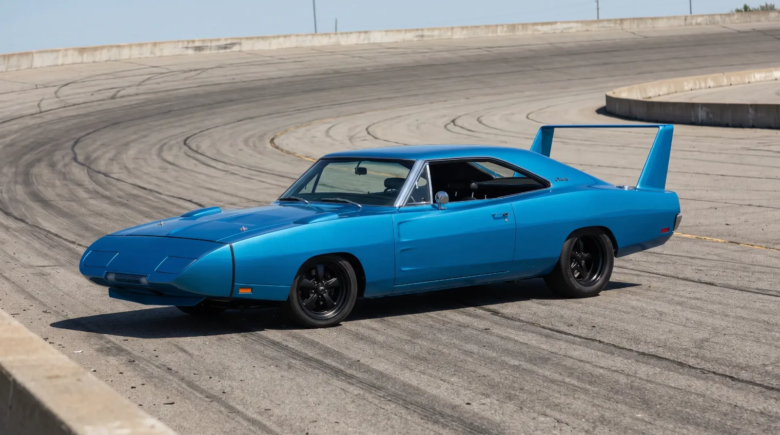 1969 Dodge Charger Daytona blue with nose cone and tall rear wing on a banked speedway