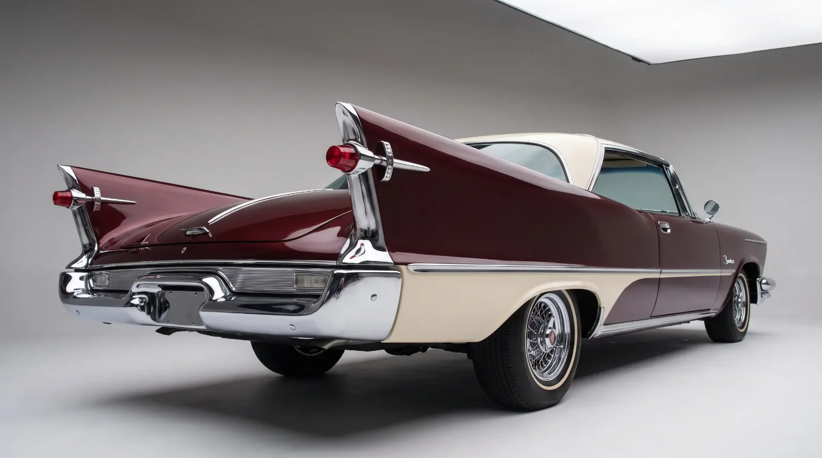 Rear three-quarter detail of a 1957 Chrysler Imperial LeBaron showing tall tailfins and freestanding gunsight taillights