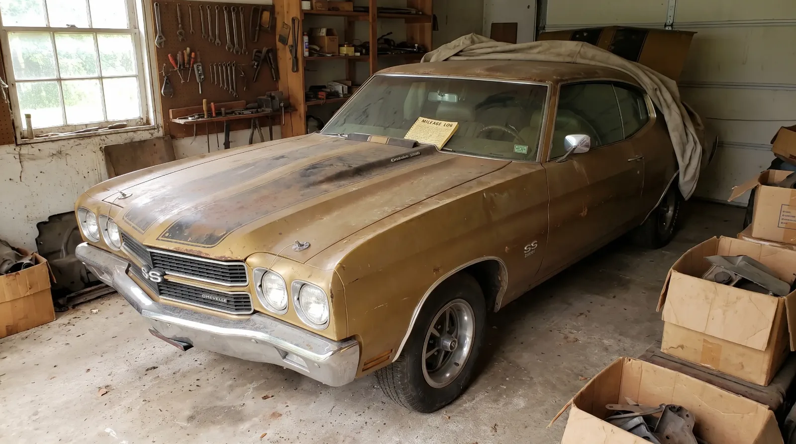 Unrestored survivor muscle car with original faded gold paint and patina in a quiet garage