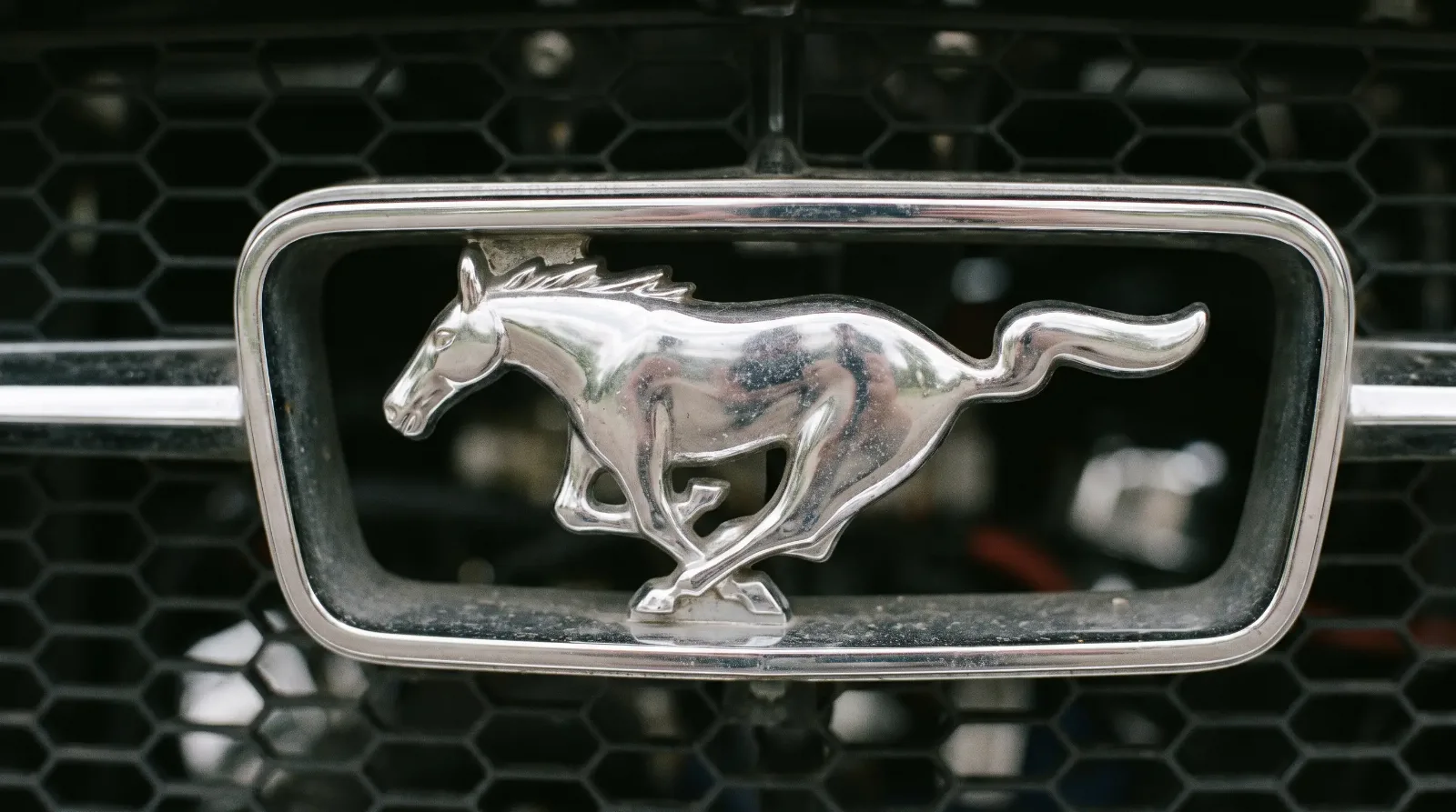 Chrome galloping-horse emblem on a classic Ford Mustang grille
