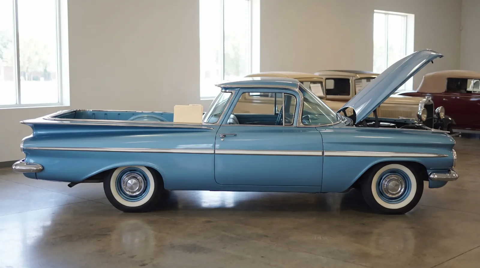 Frost Blue 1959 Chevrolet El Camino with hood open on a classic car showroom floor