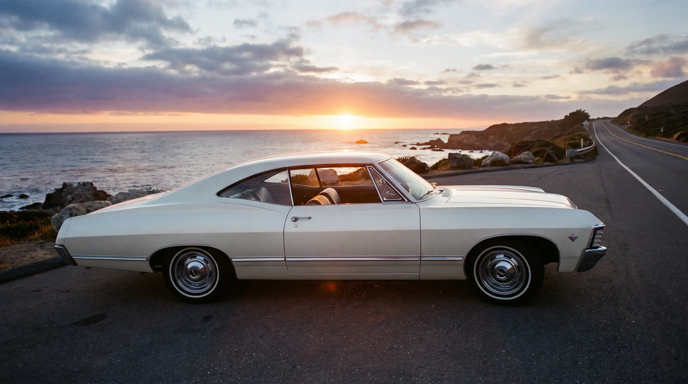 White 1967 Chevrolet Impala showing coke bottle body curves on a coastal road