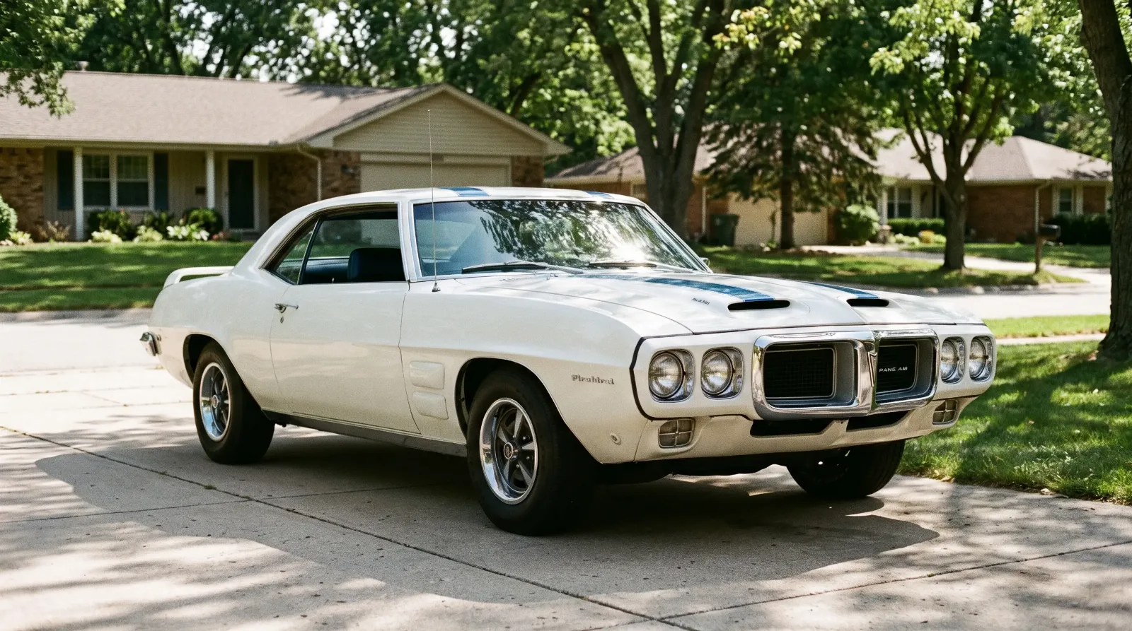 White 1969 Pontiac Firebird Trans Am with blue stripes parked on a residential driveway