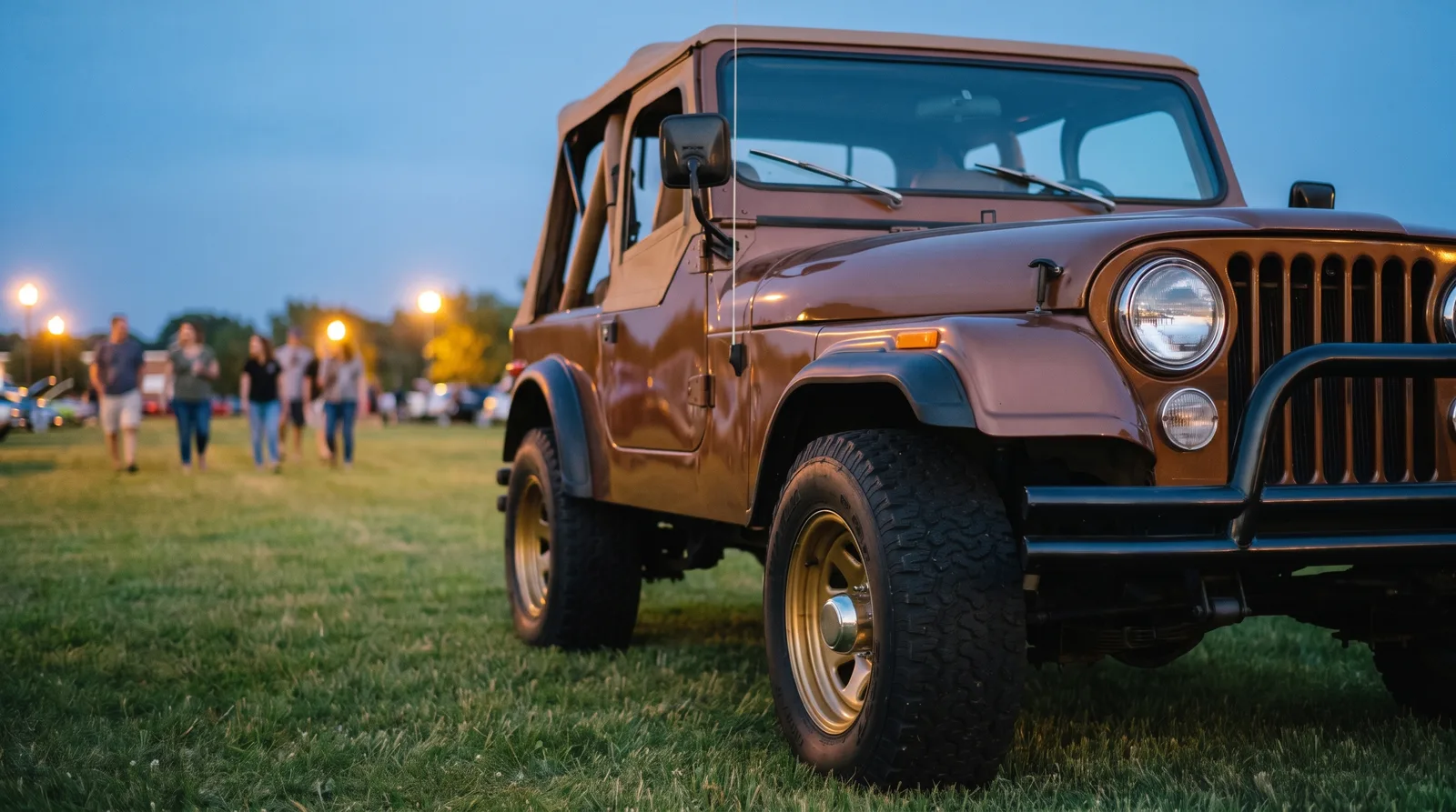 1977 Jeep CJ-5 Golden Eagle, gold wheels on a car show lawn at dusk
