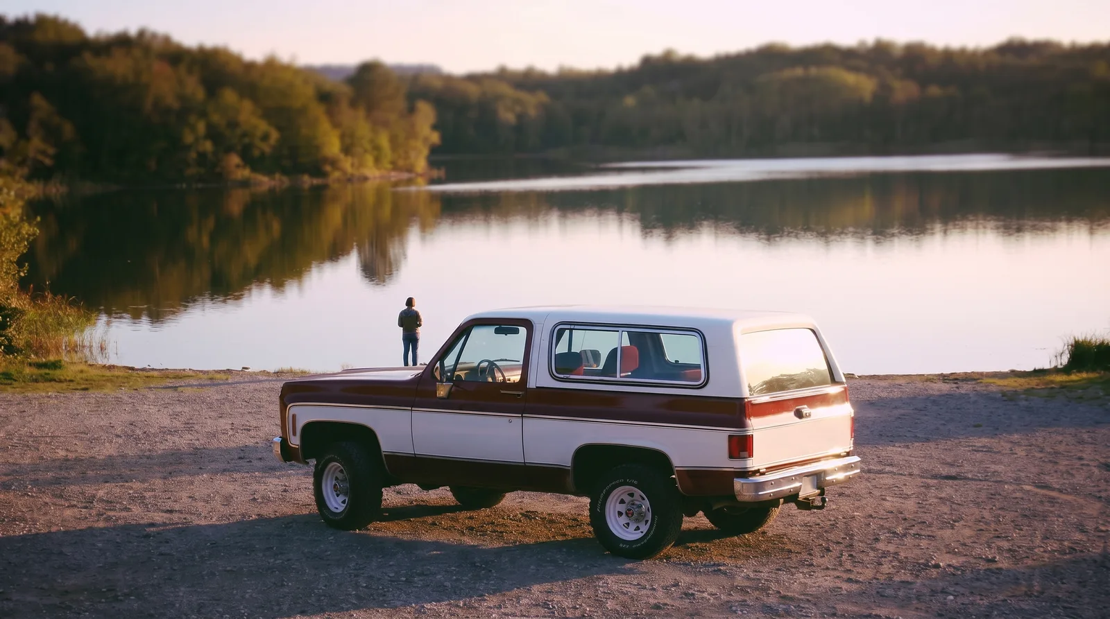 1980 GMC Jimmy â€” two-tone paint on a lakeside gravel lot