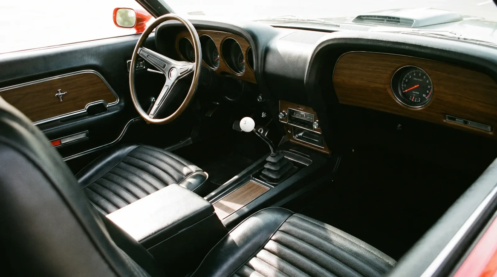 Interior of a 1969 Ford Mustang Mach 1 showing the four-speed manual shifter and console