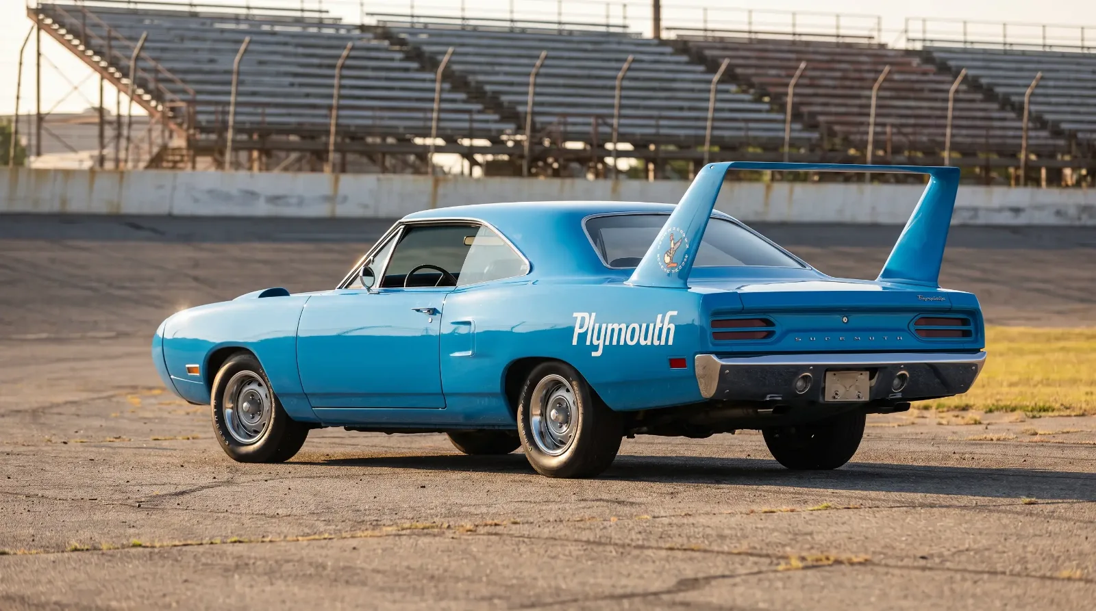 1970 Plymouth Superbird petty blue with tall rear wing on a vintage speedway apron
