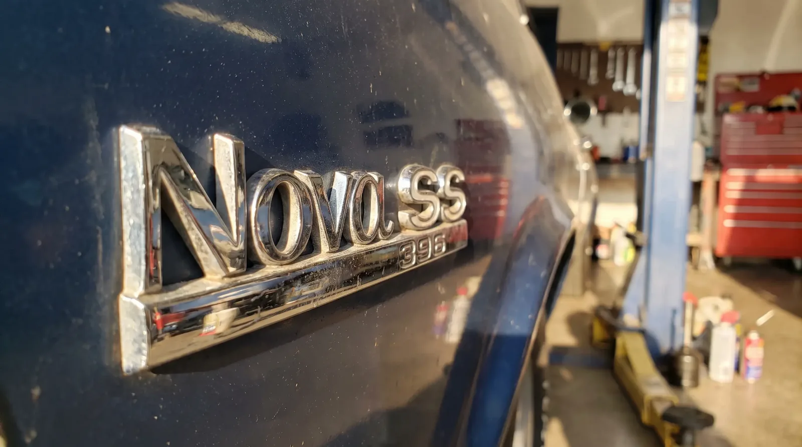 Macro close-up of a chrome Chevrolet Nova SS 396 fender emblem catching sunlight