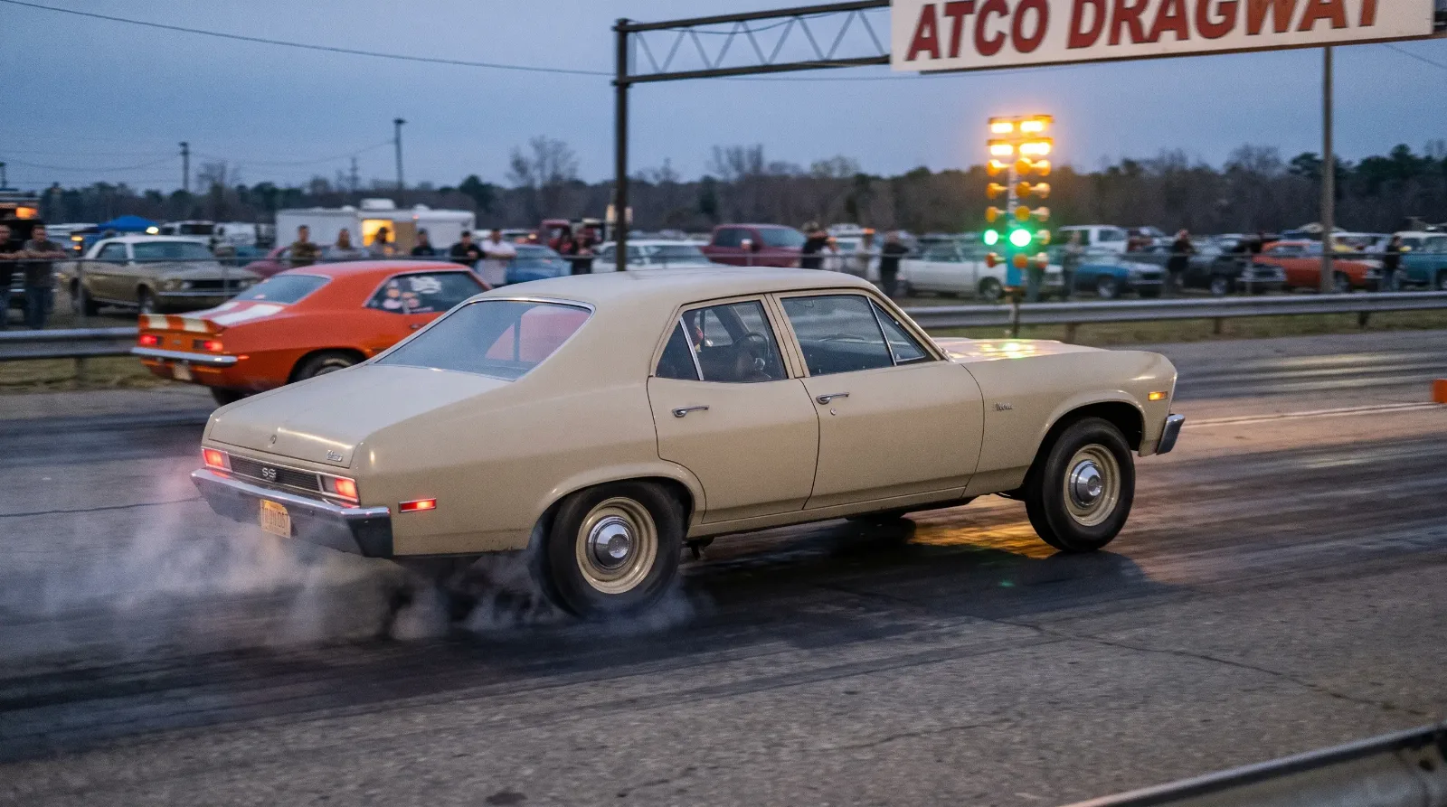 Plain beige 1969 Chevrolet Nova SS 396 launching hard at a period drag strip at dusk