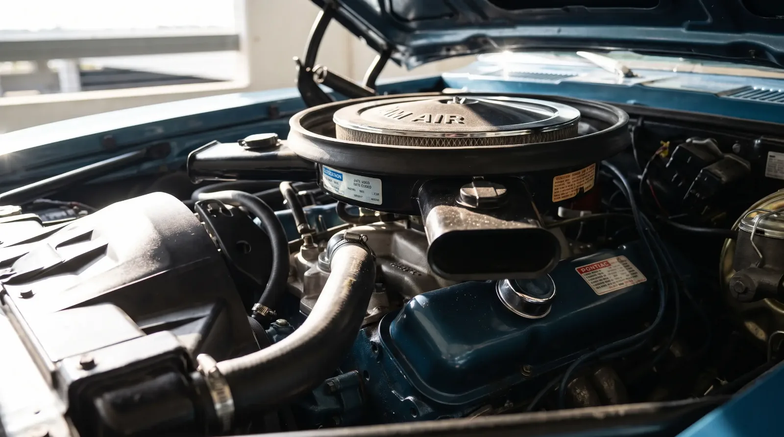 Close-up of a 1969 Pontiac 400 Ram Air V8 engine bay with chrome air cleaner and functional hood scoop ducting