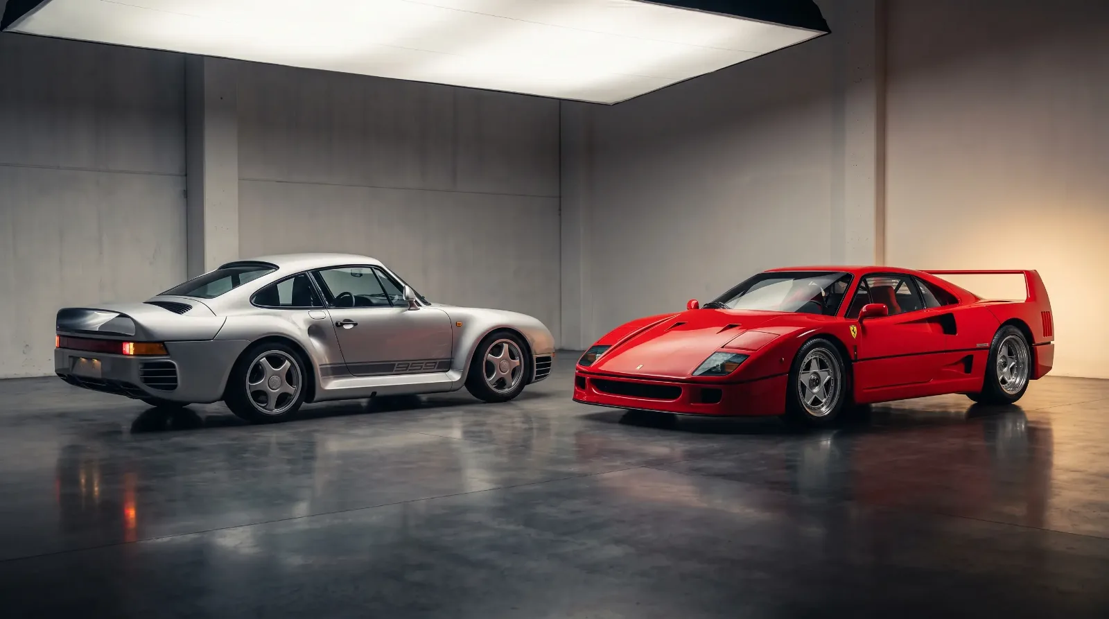 Silver Porsche 959 and red Ferrari F40 parked nose to nose in a studio showroom