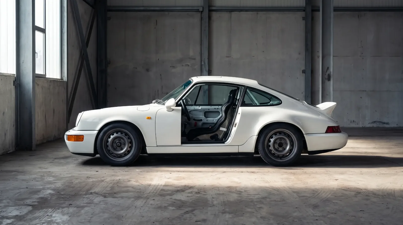 White 1992 Porsche 964 Carrera RS parked in a concrete garage bay with door open