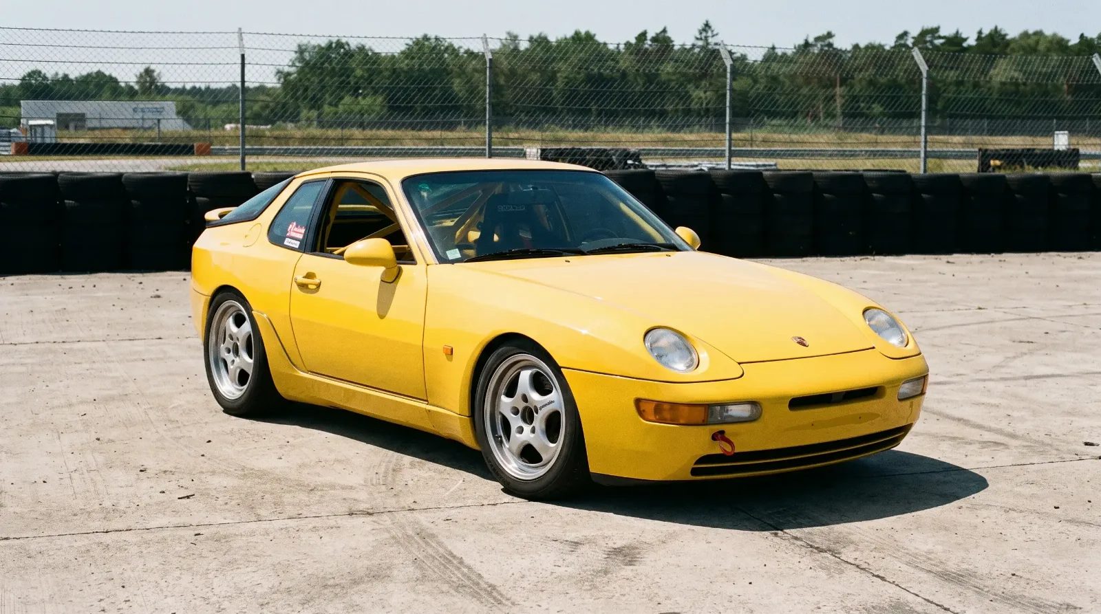 1993 Porsche 968 Club Sport in yellow at a track paddock, three-quarter front view