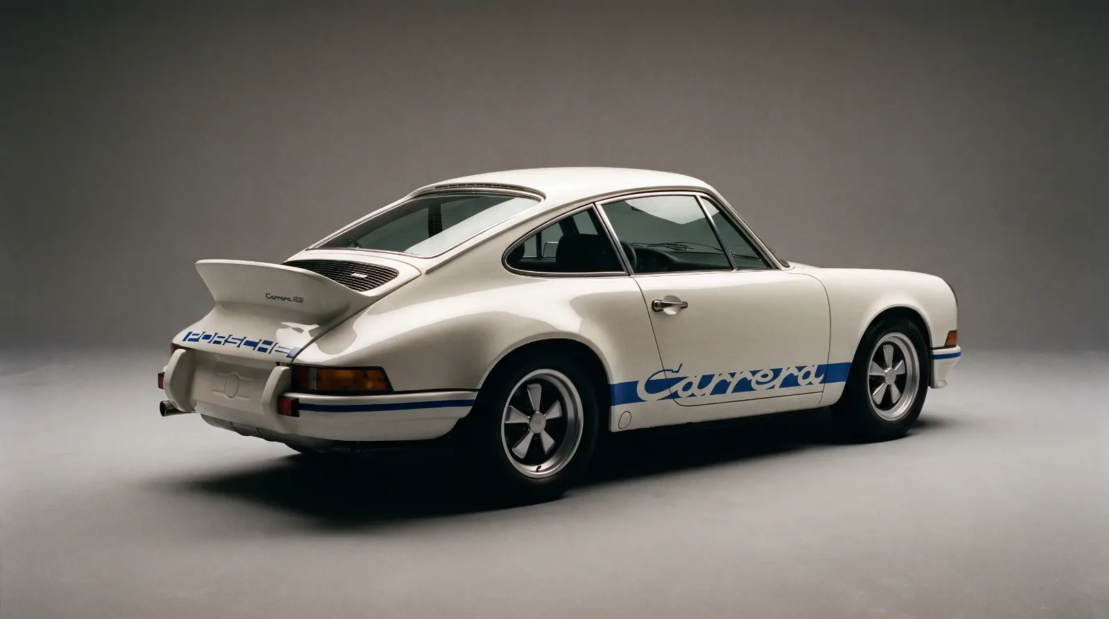 Studio shot of a Grand Prix White 1973 Porsche Carrera RS 2.7 showing its ducktail spoiler and Fuchs wheels