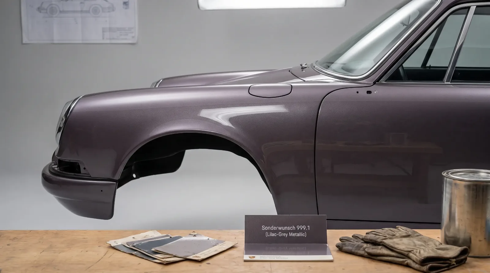 Close detail of a classic Porsche 911 fender in a rare paint-to-sample metallic color with color swatches on a studio workbench