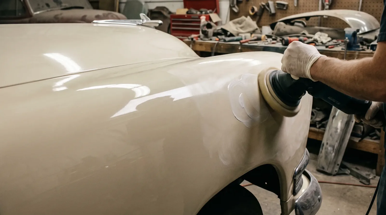 Hand buffing a freshly painted cream 1950s fender with compound, half the panel polished to a deep gloss