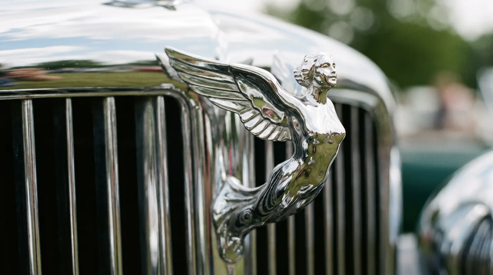 Chrome winged figurine hood ornament on a classic grille