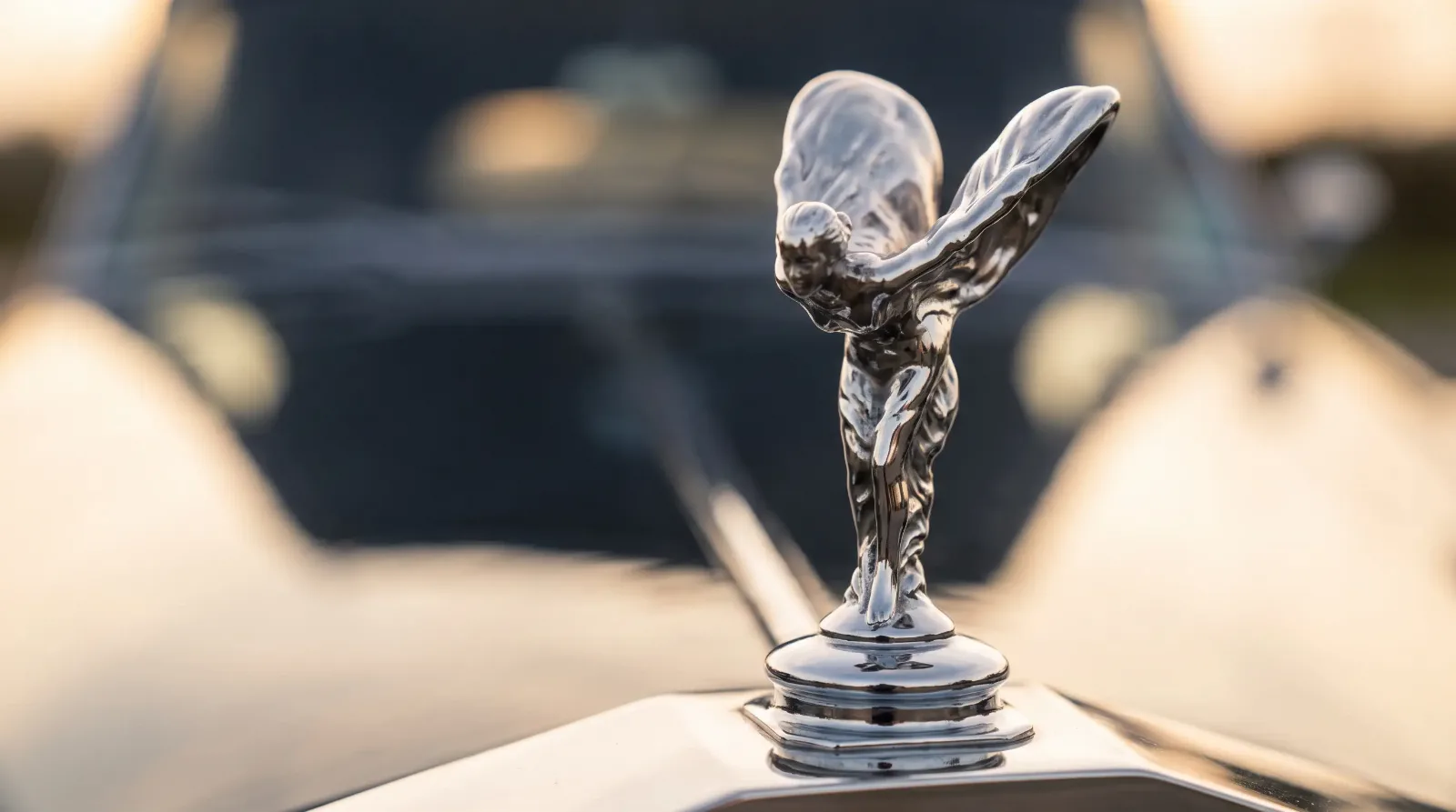 Close-up of the Spirit of Ecstasy chrome hood ornament atop a classic Rolls-Royce radiator shell