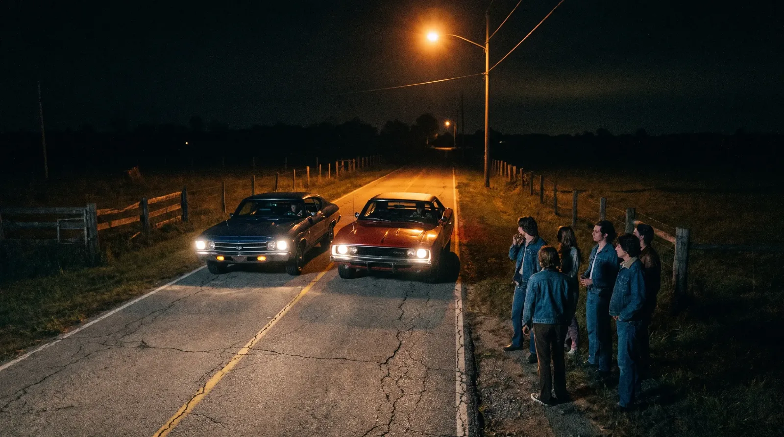Two 1960s muscle cars staged for a night street race on a two-lane road